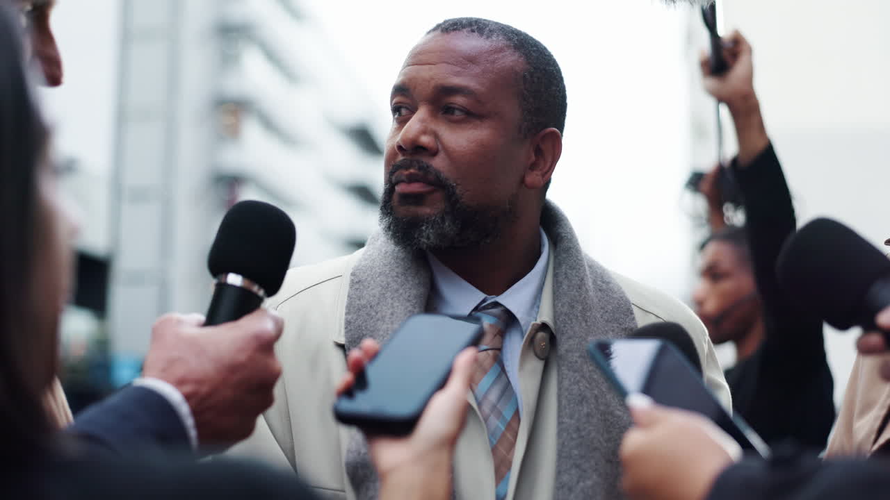 Man giving a press conference while surrounded by reporters