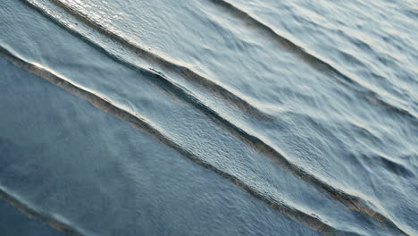 Twisting-waves-of-shoreline-in-France-riverside-ocean-water-splashes-abstract-background-meditation-yoga-windy-breeze-gimbal-turning-reflective-surface-shallow-relaxing-dance-ballet-blue-drops-nature