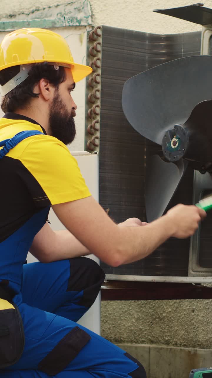 Vídeo vertical de un ingeniero de climatización limpiando con un plumero el ventilador del soplador