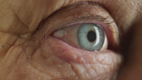 close up blue eye opening old woman blinking macro aging beauty optometry concept