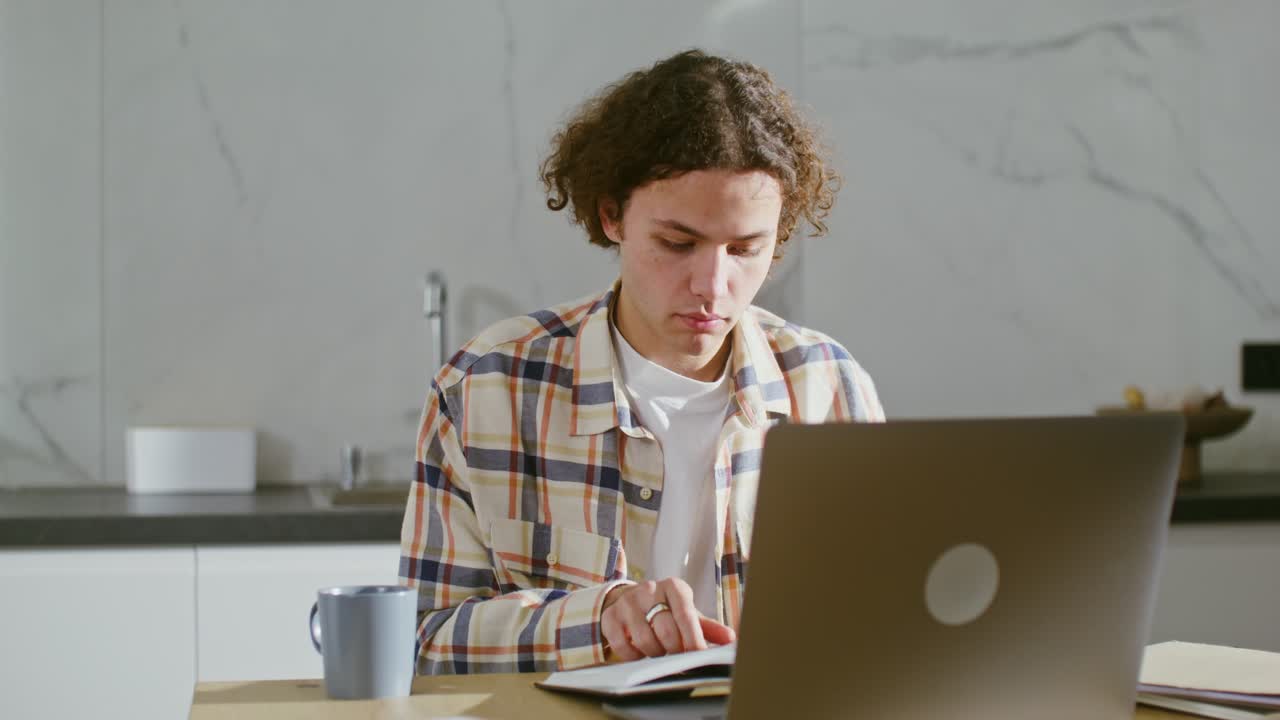 joven adulto estudiando en casa con portátil y libro