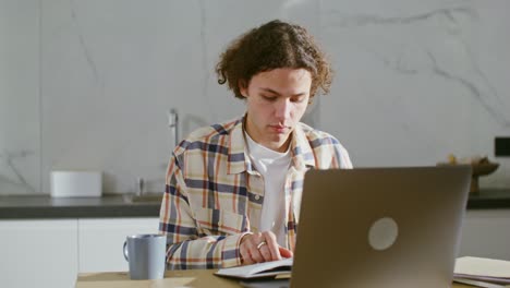 joven adulto estudiando en casa con portátil y libro