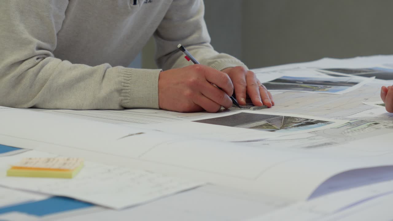 Architect hands sketch building plans on a blueprint at desk