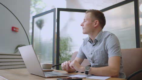 young thoughtful business man thinking of problem solution working on laptop. serious doubtful male professional looking away at laptop considering market risks making difficult decision