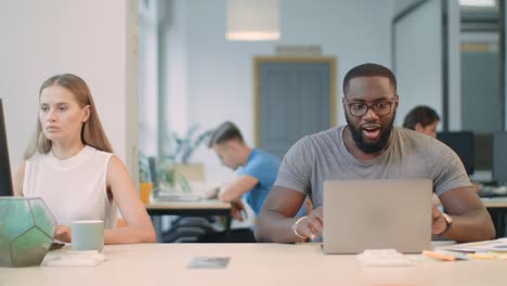 happy african man reading good news on laptop computer at coworking space