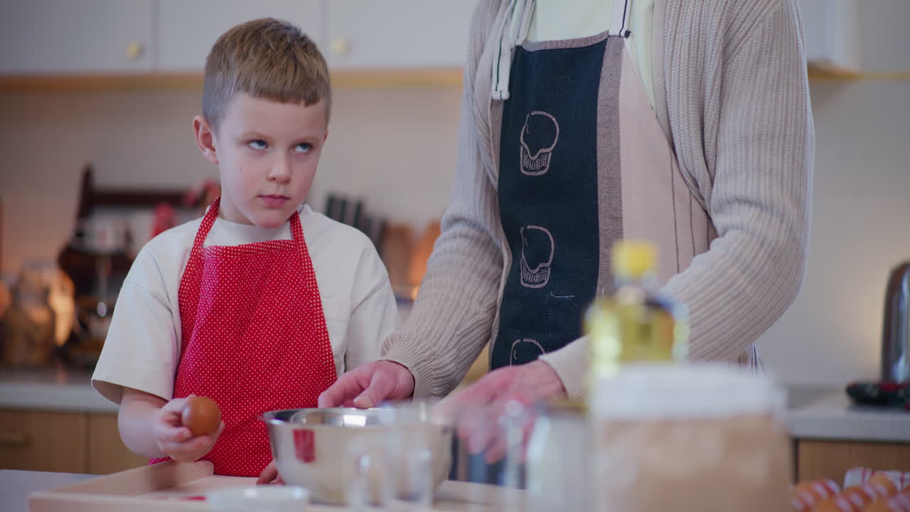 un niño rompe un huevo en masa con la ayuda de su padre.