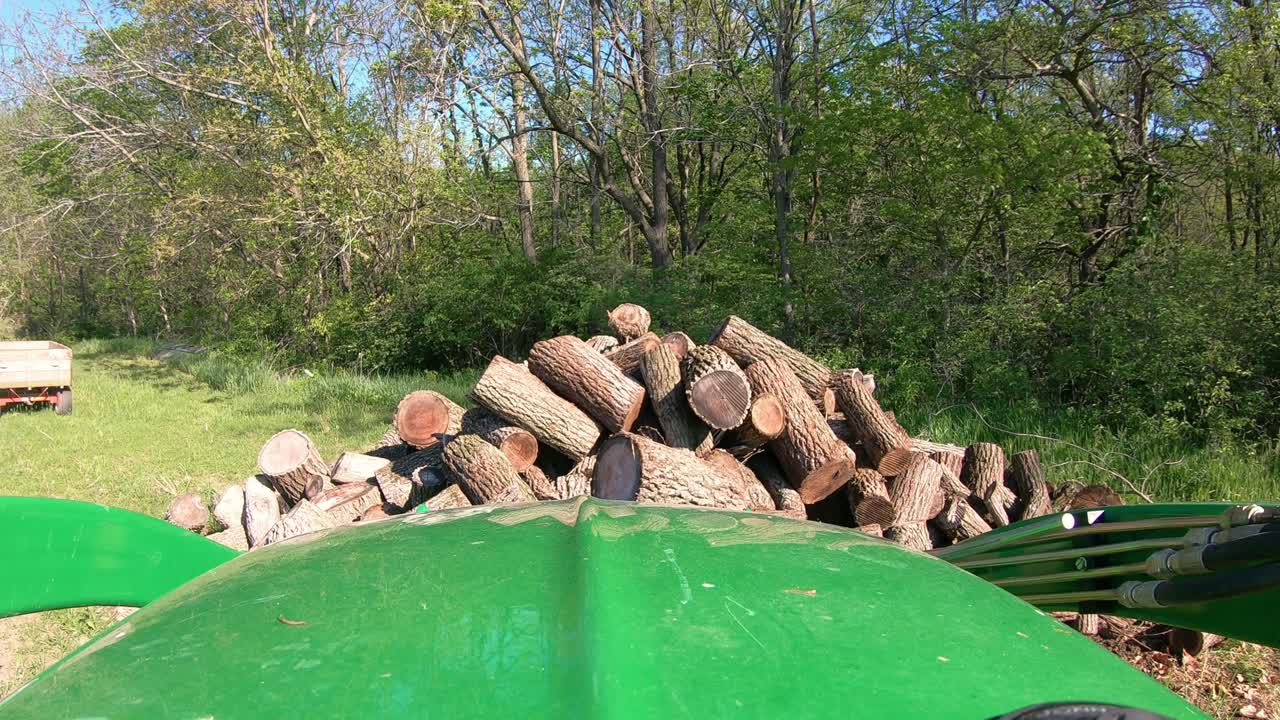 pov mientras opera un tractor verde con horquillas hidráulicas para mover troncos cortados