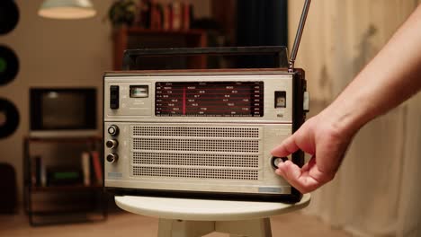 person adjusting vintage radio in a living room