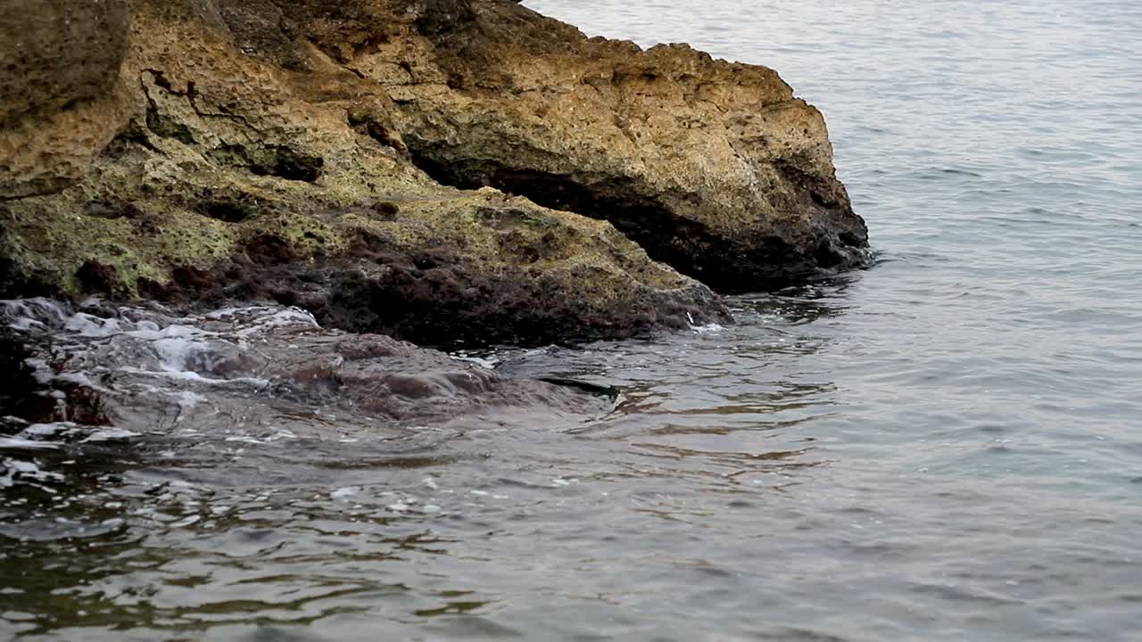 Onde calme che colpiscono le rocce in una giornata cupa.