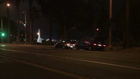 un auto viaja a lo largo de una calle en la noche en santa monica california como se ve a través de la ventana trasera en un ángulo 6
