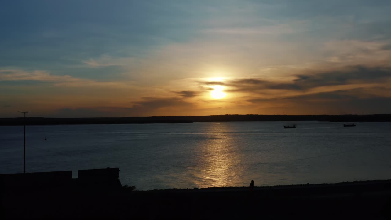 Stunning aerial drone dolly out shot of a golden sunset reflecting onto the water and the camera passing over a famous historical military fort in Joao Pessoa, Brazil