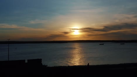 impresionante toma aérea de drones de una puesta de sol dorada que se refleja en el agua y la cámara pasa sobre un famoso fuerte militar histórico en joao pessoa, brasil