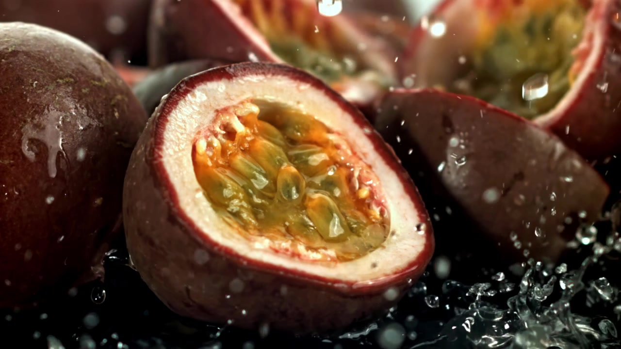 Super slowmotion af vand, der plasker på frisk halveret passionsfrugt