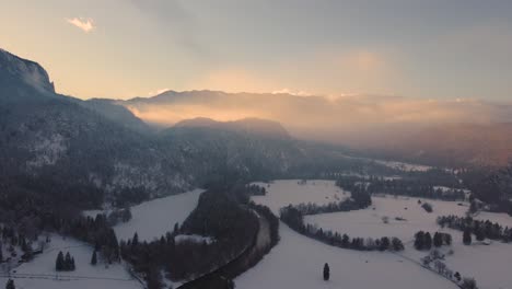 drone shot of a mysterious landscape at sunset in the mountains covered with clouds in wintertime