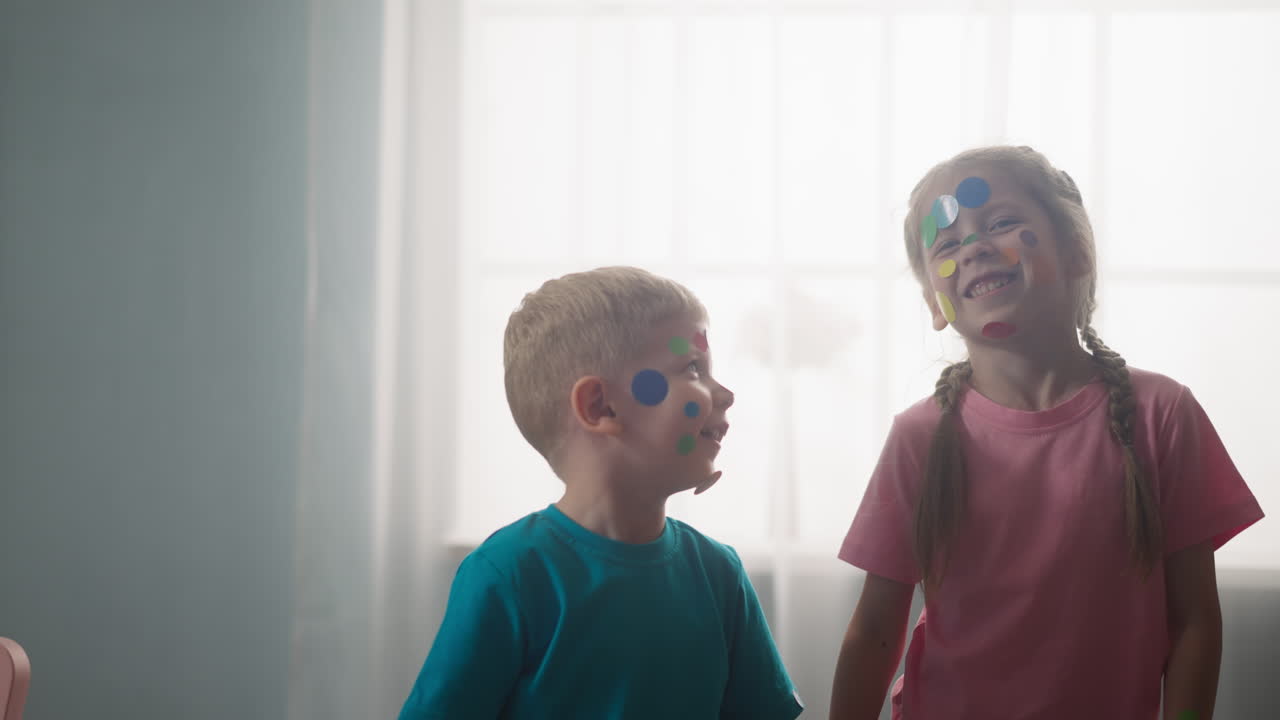 niños pequeños con pegatinas de colores en sus rostros, expresan alegría
