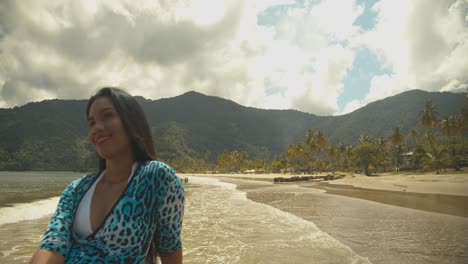 bella modelo posando en una playa en la isla caribeña de trinidad con montañas al fondo