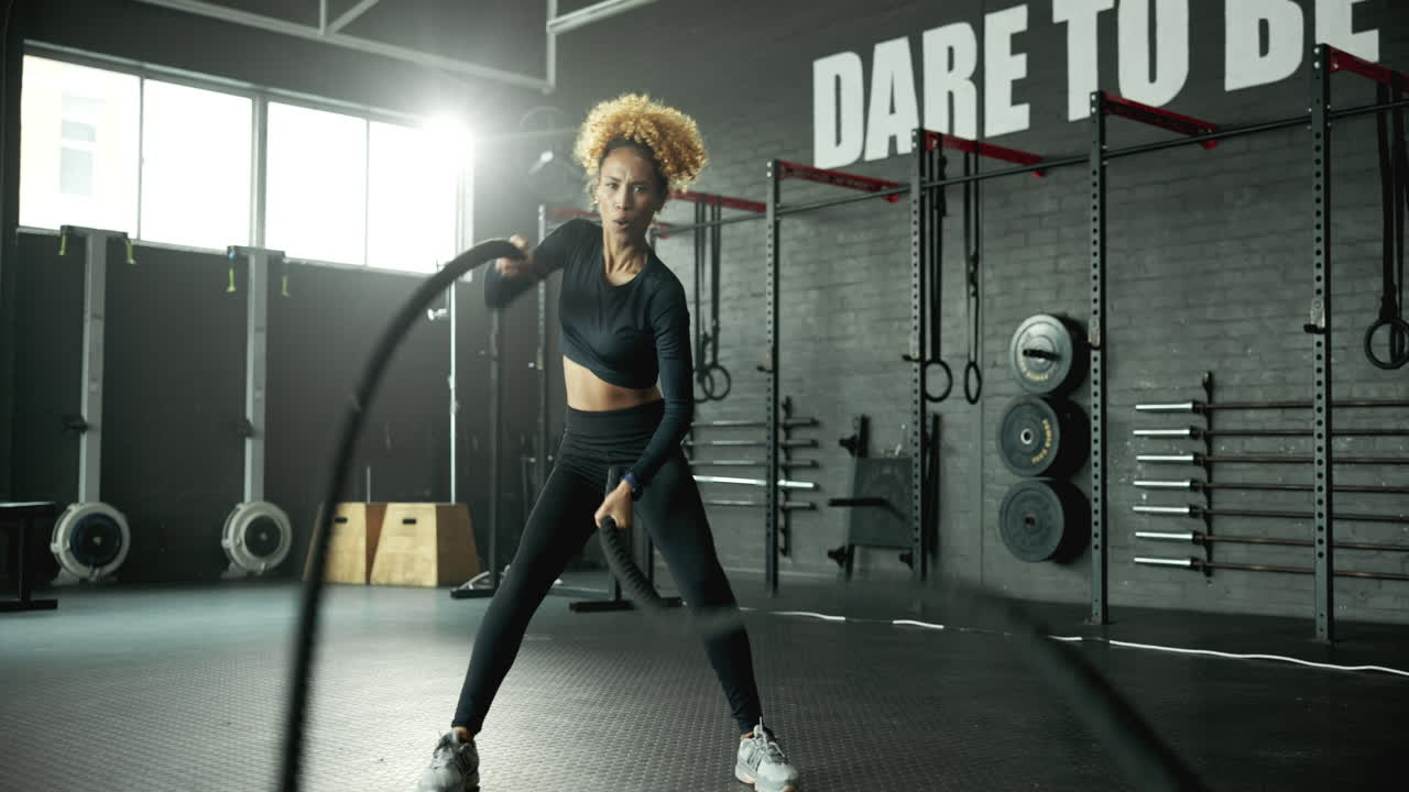 Woman working out with battle ropes in the gym