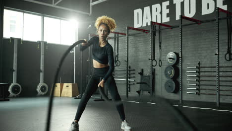 woman working out with battle ropes in the gym
