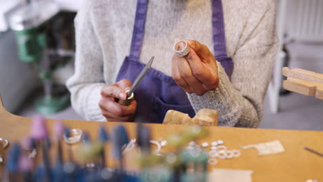 Close-Up-Of-Female-Jeweller-Working-On-Ring-With-File-In-Studio