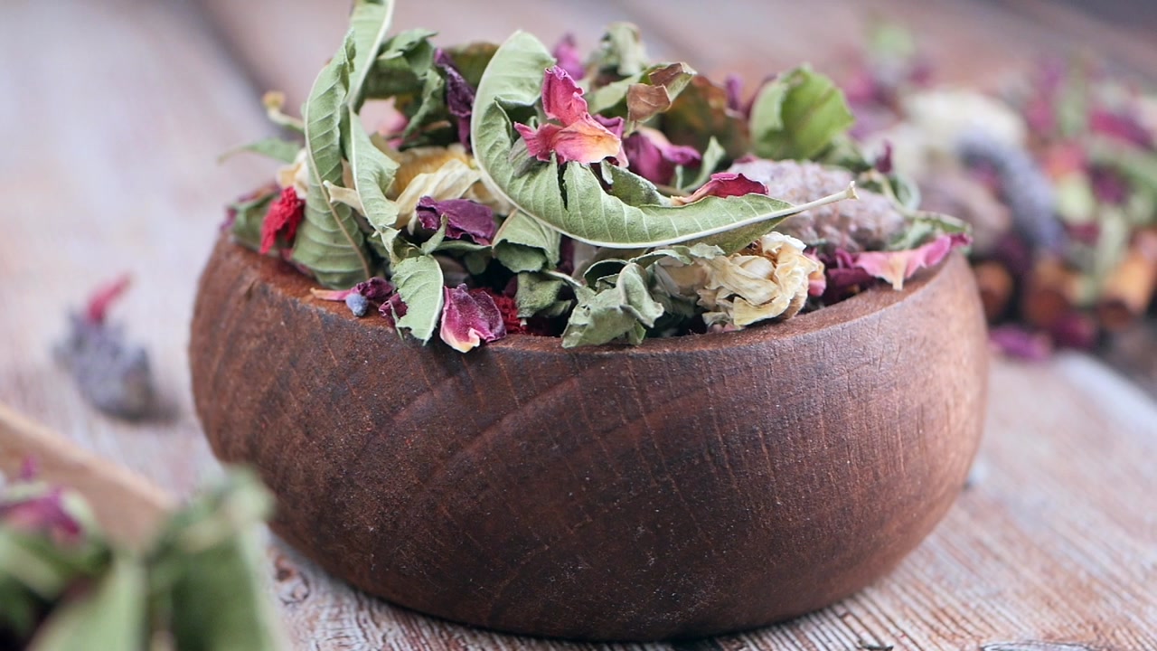 Dried Herbs and Flower Petals in a Rustic Wooden Bowl