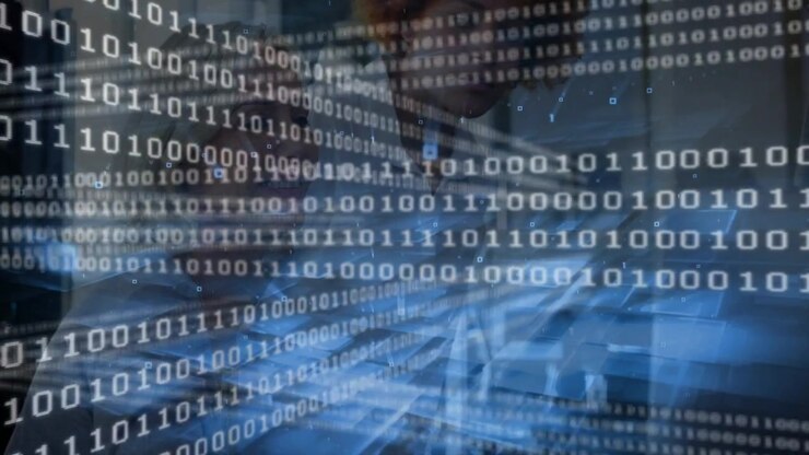 Two women typing at laptop, input shifting binary overlay while collaborating on data security