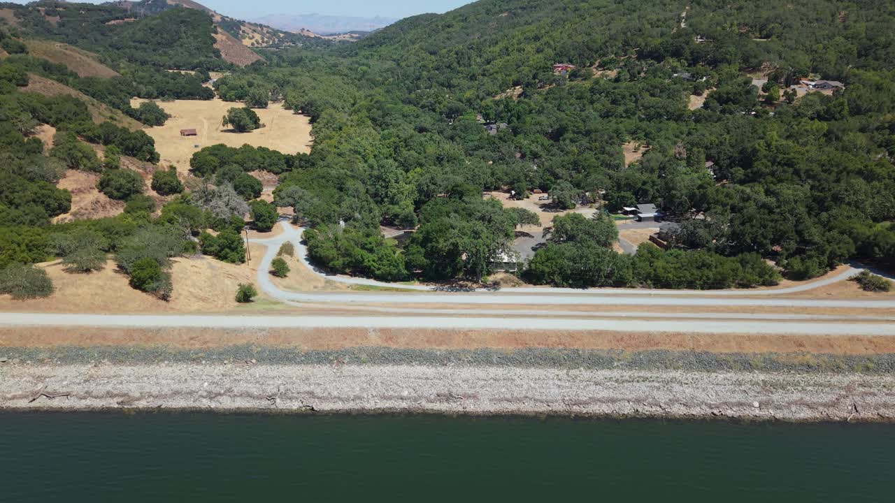 Soaring above Uvas Reservoir Dam, the drone captures the textured terrain with gentle motion