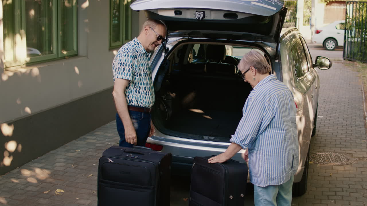 Senior couple packing luggage into car trunk for travel