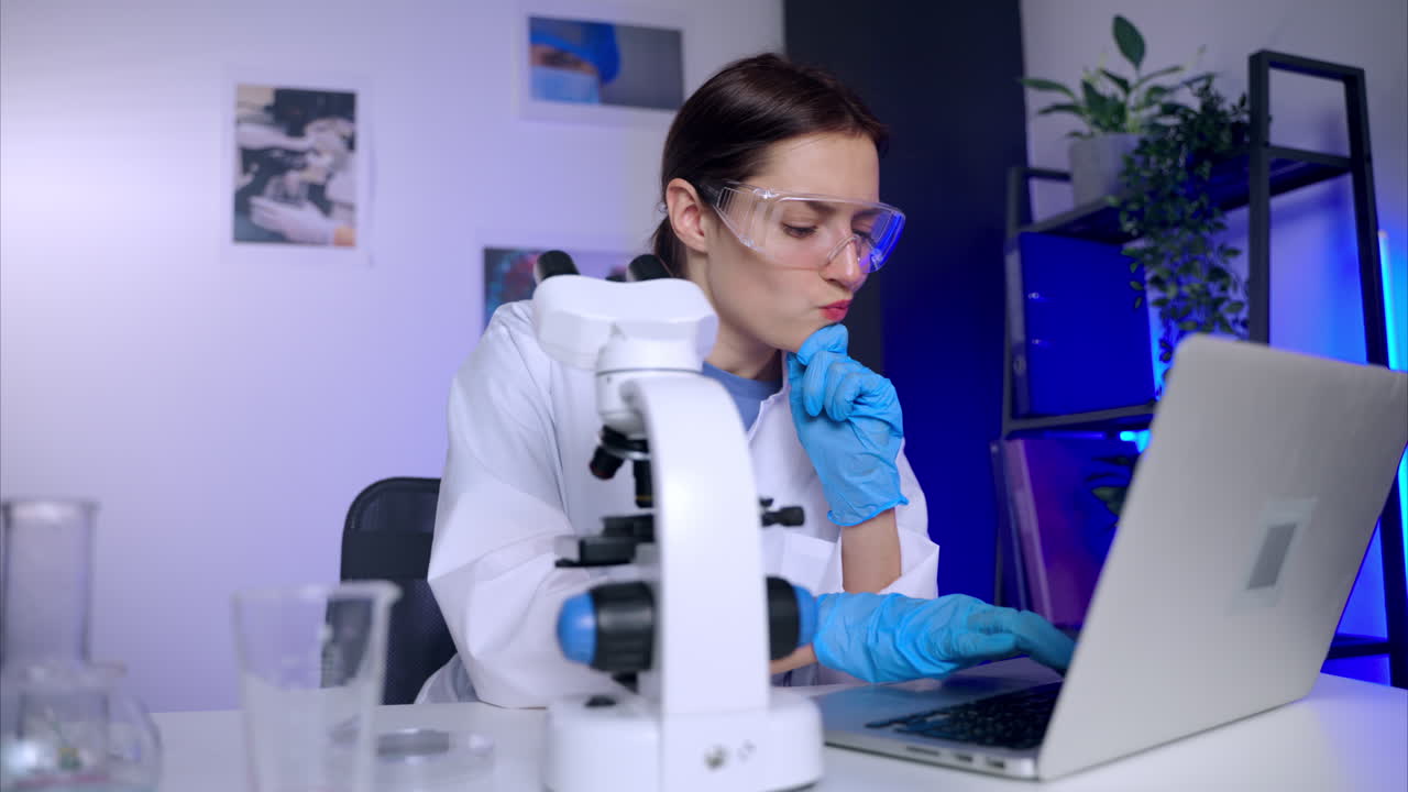 Scientist working with microscope and laptop in a lab
