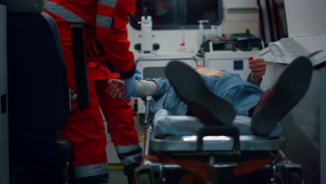 paramedics proving first aid to patient. doctors applying bandage on hand of man