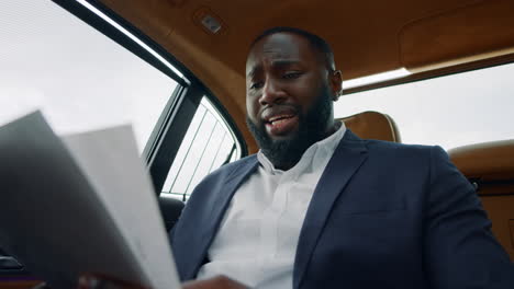 African-man-reading-documents-at-car