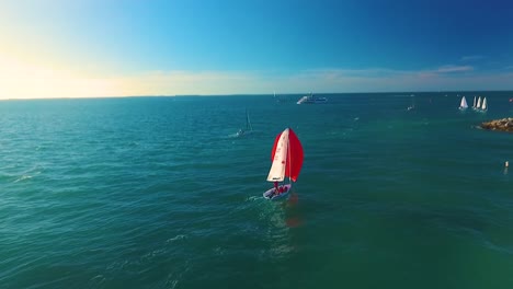 As-a-sailboat-quietly-floats,-the-camera-rapidly-approaches-while-tilting-down-in-sharp-4K-resolution