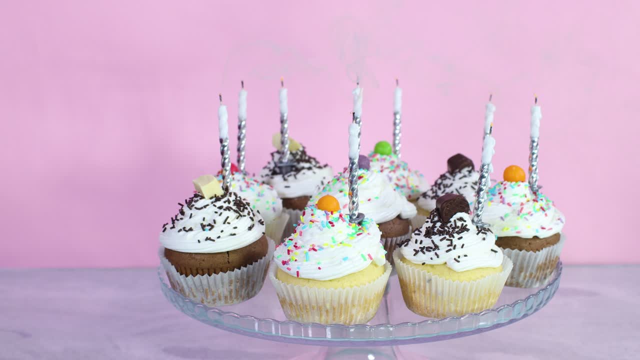Blowing candles on cup cakes with cream for birthday party