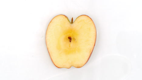 On a white background sliced Apple slices are sprinkled with water