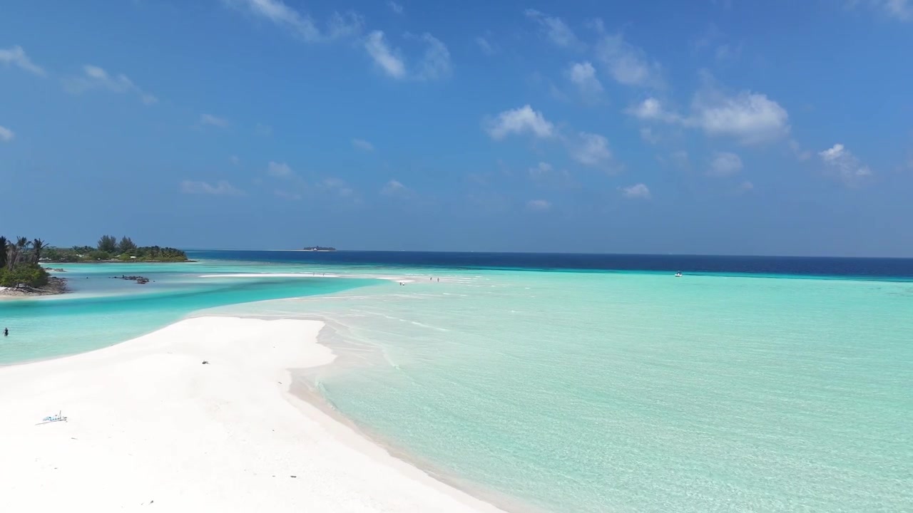 Ampia ripresa aerea con drone di un banco di sabbia bianco che circonda una laguna oceanica turchese cristallina alle Maldive.