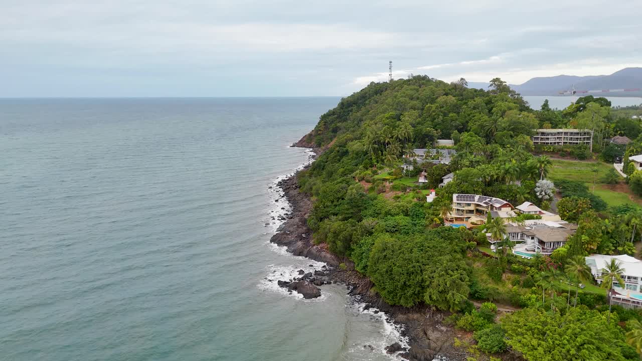 Drone captures lush greenery and coastal scenery in Port Douglas, Australia. Overcast skies create a serene, natural atmosphere