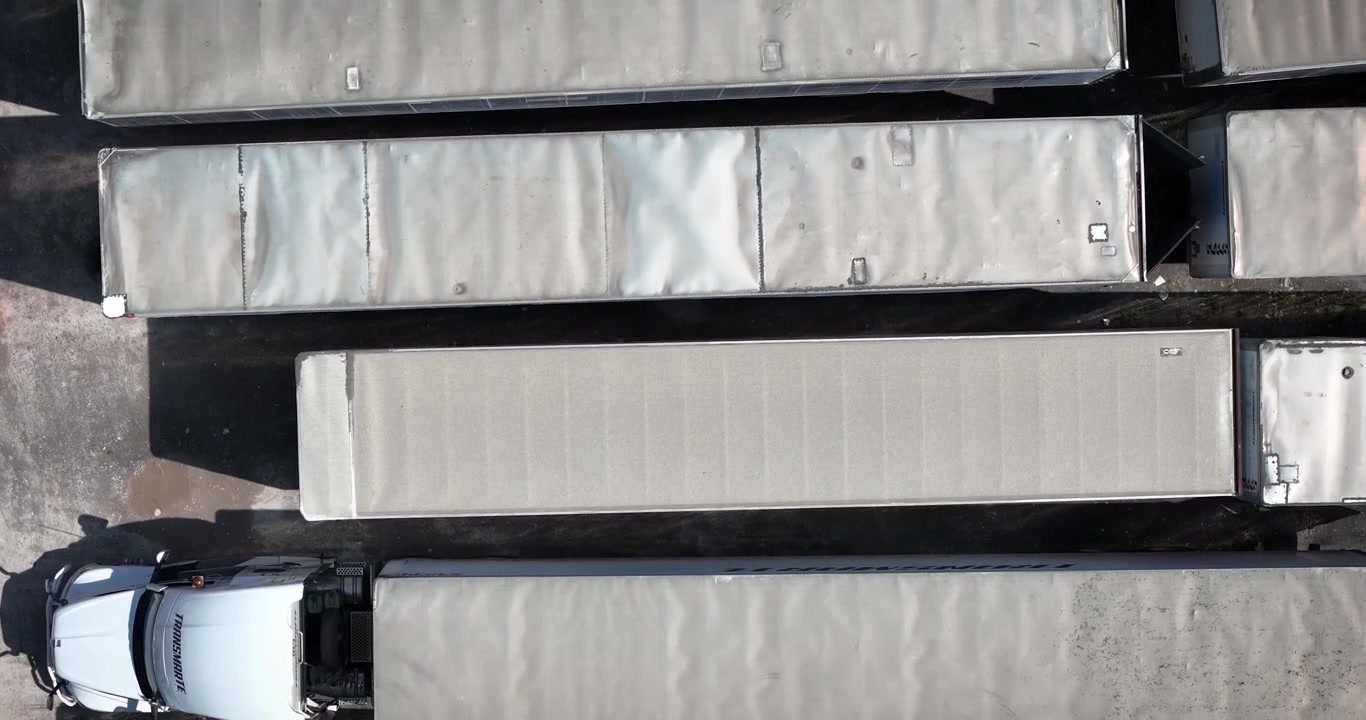 Top-down aerial view of cargo trailers and commercial trucks parked in parallel inside a logistics yard in Tepotzotlan, Mexico, highlighting freight transportation and supply chain operations.