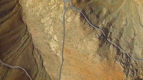 aerial view of a car driving on a winding mountain road in fuerteventura.