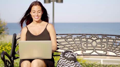 Attractive-woman-typing-on-her-laptop-outdoors