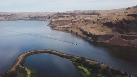 aerial, panoramic view following a speedboat down the palouse river and into the snake river in the scablands of eastern washington state