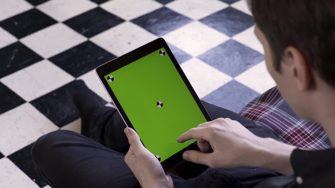 녹색 화면을 가진 태블릿을 사용하는 사람