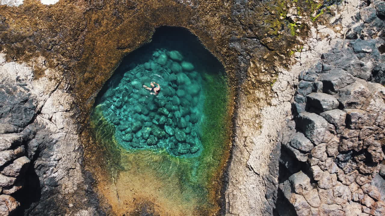 Berenang dan mengapung di teluk dengan air pirus, Fuerteventura.