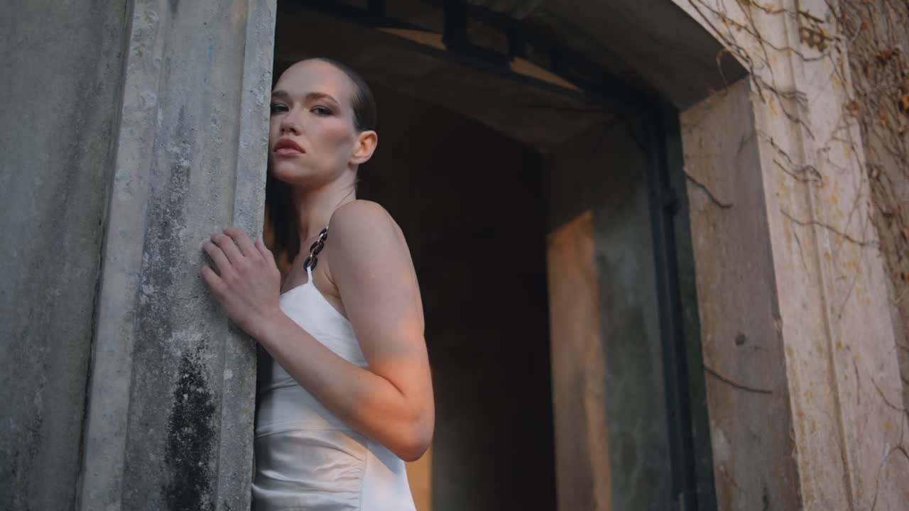 고급스러운 여인이 벽을 만지고 가을에 오래된 중세 건물. 성을 포즈하는 소녀