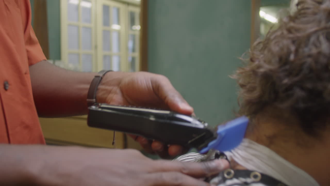 African American Barber Cutting Hair of Client with Hair Clippers