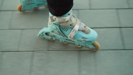 un primer plano que captura el movimiento de los patines que se deslizan suavemente sobre un camino pavimentado en un parque. la persona que lleva los patines está vestida con pantalones negros, haciendo hincapié en el movimiento fluido