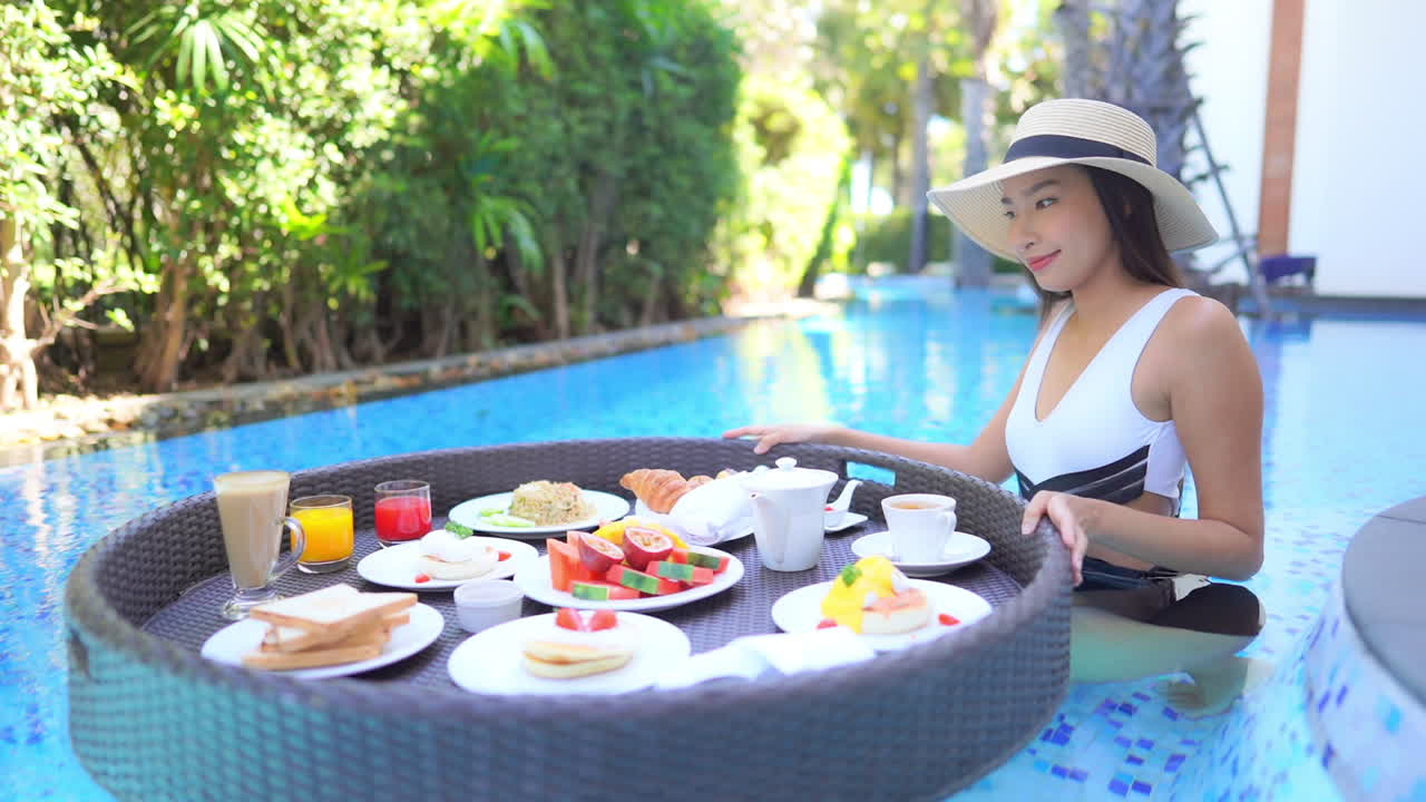 Breakfast For Two on Floating Pool Plate. Happy Asian Female on Luxury Vacation. Slow Motion
