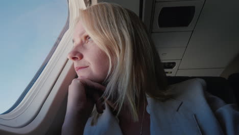 portrait of a confident female passenger flying in an airplane looking out the window