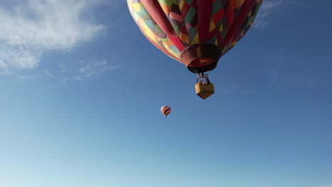 Colorful-Hot-Air-Balloons-Flying-Under-Blue-Sky-on-Sunny-Day,-Low-Angle-Aerial-View