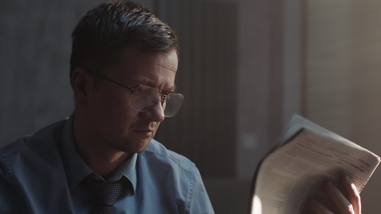 A sad man in a shirt reads a newspaper