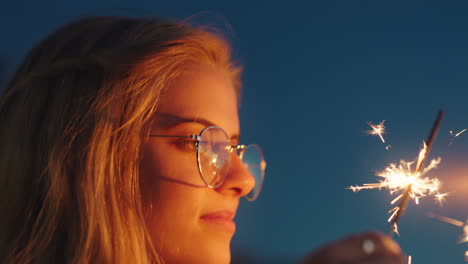 Frau-Spielt-Mit-Wunderkerzen-Am-Strand-Bei-Sonnenuntergang-Und-Genießt-Die-Silvesterfeier-Mit-Blick-Auf-Die-Feuerwerksfunken.-Mädchen-Feiert-Den-Unabhängigkeitstag