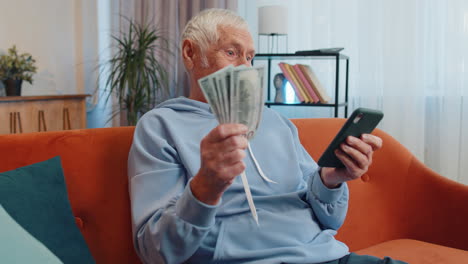 sonriendo feliz anciano anciano abuelo contando dinero efectivo uso de teléfono inteligente, ingresos, ahorros, ganar la lotería